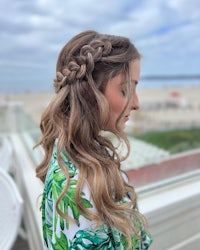 a woman wearing a green shirt and braided hair on a balcony overlooking the beach